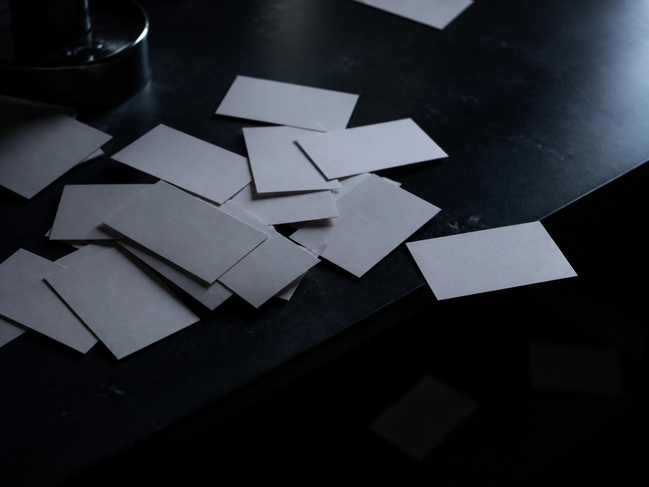 Tarjetas de papel dispersas y olvidadas sobre un escritorio oscuro